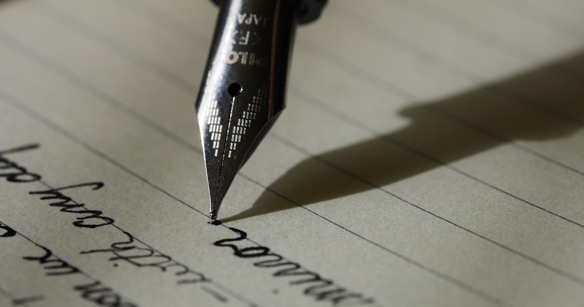 A teacher writing a college recommendation letter with a fountain pen